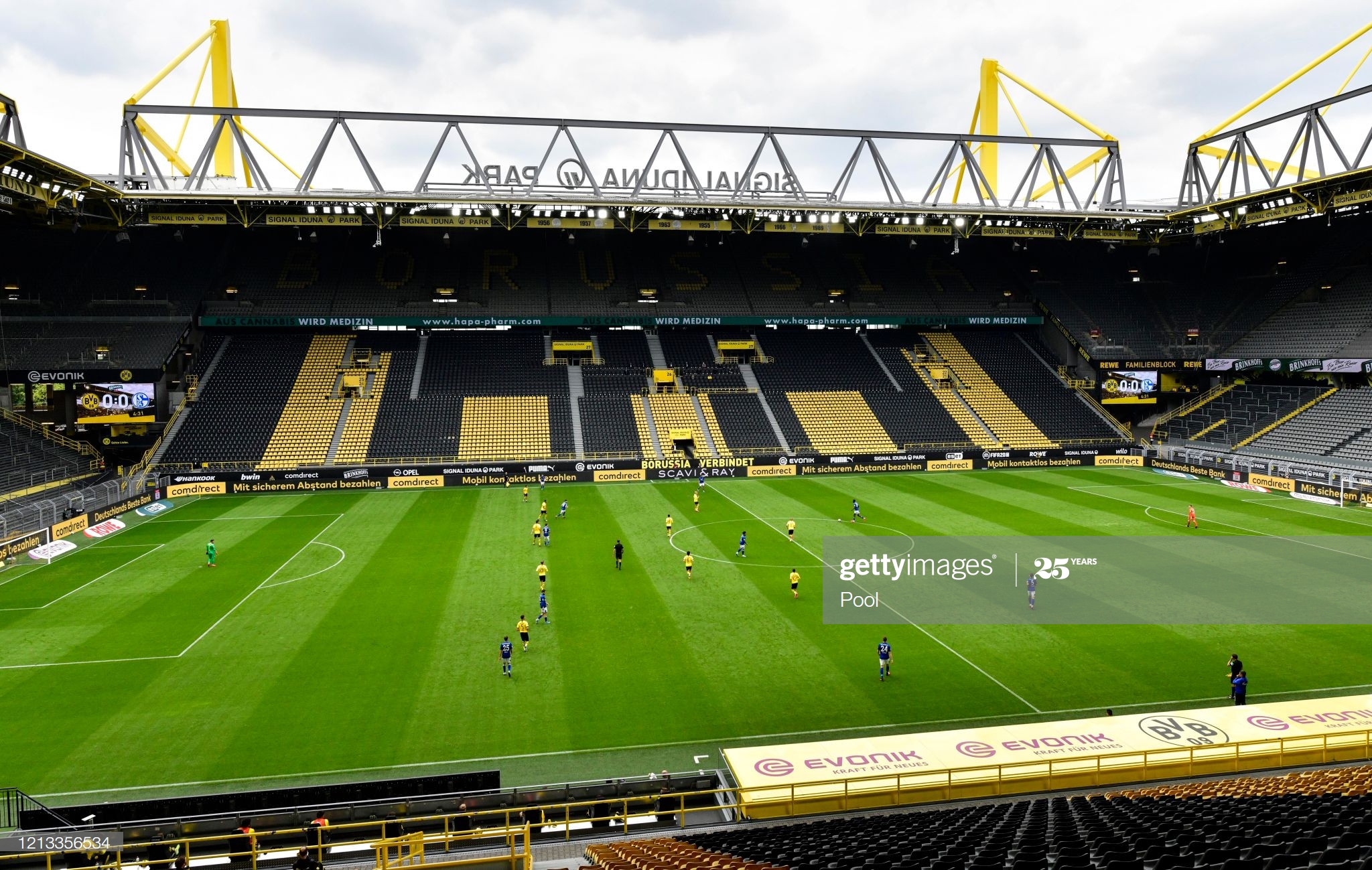 Borussia Dortmund and Schalke players compete inside an empty Signal Iduna Park.