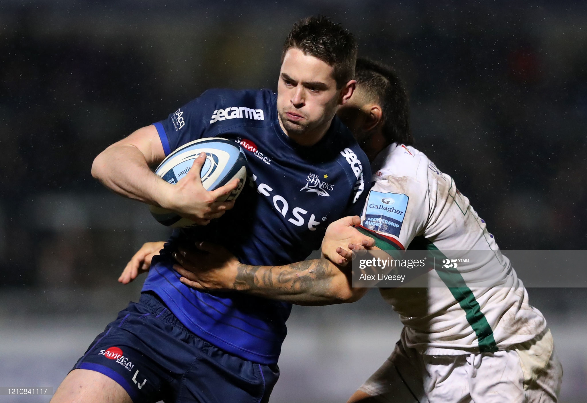 man in blue shirt running with a rugby ball
