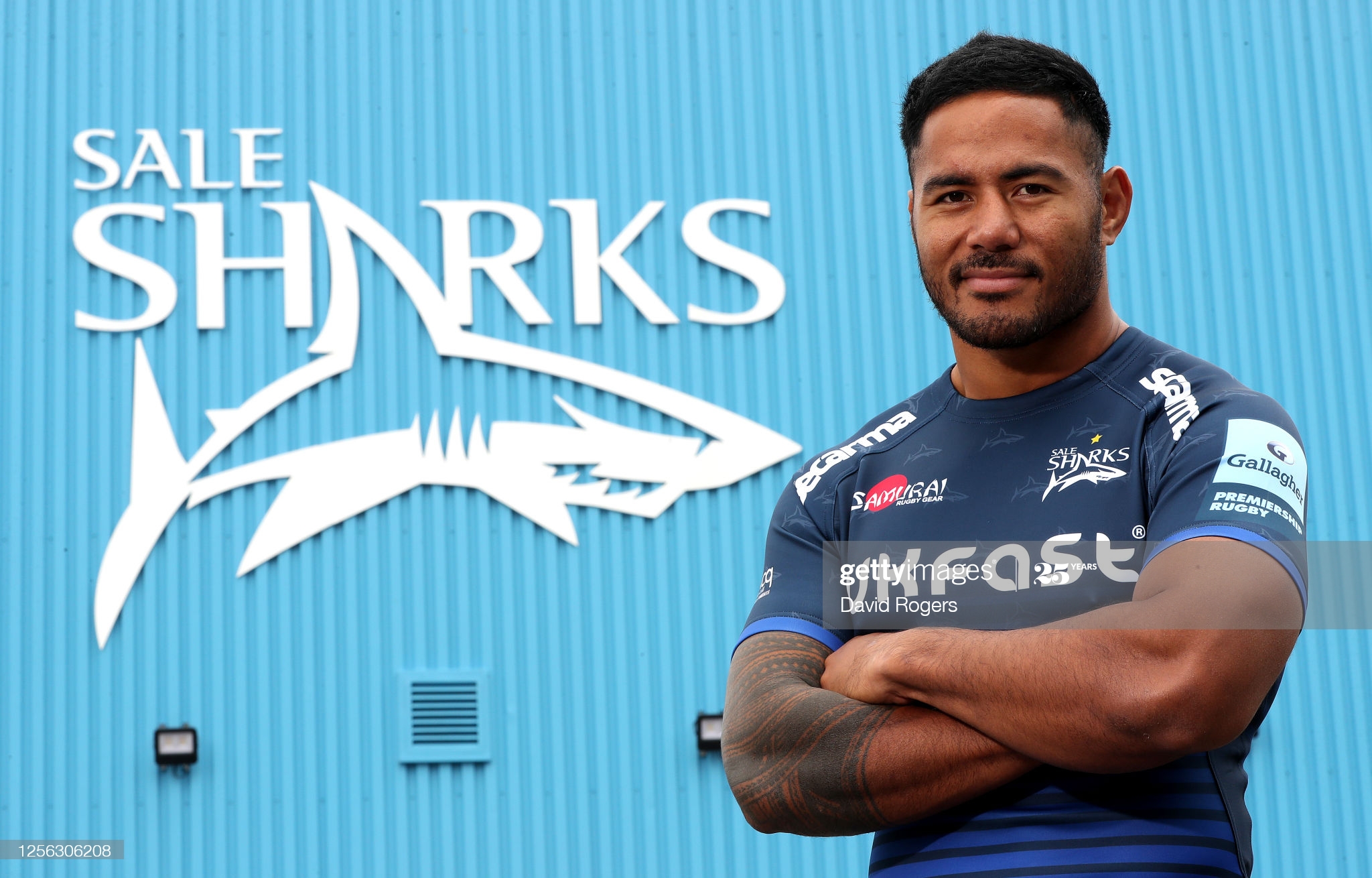 Man in blue shirt and shorts standing in front of blue wall with Sale Sharks logo on