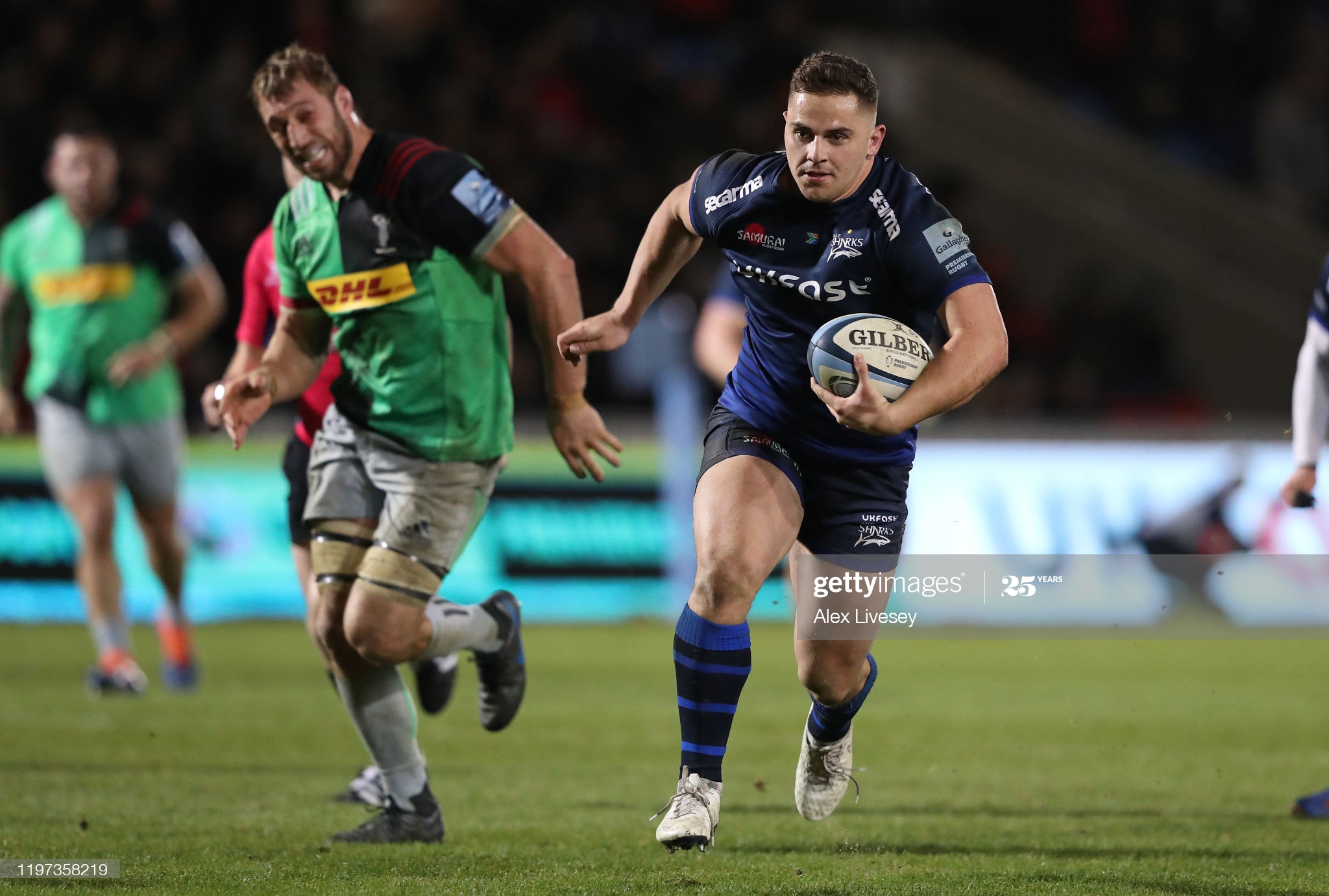 Man in blue shirt and shorts running with a rugby ball