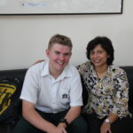 Jake, wearing his school uniform, sits beside Shireen, his special needs assistant at secondary school.