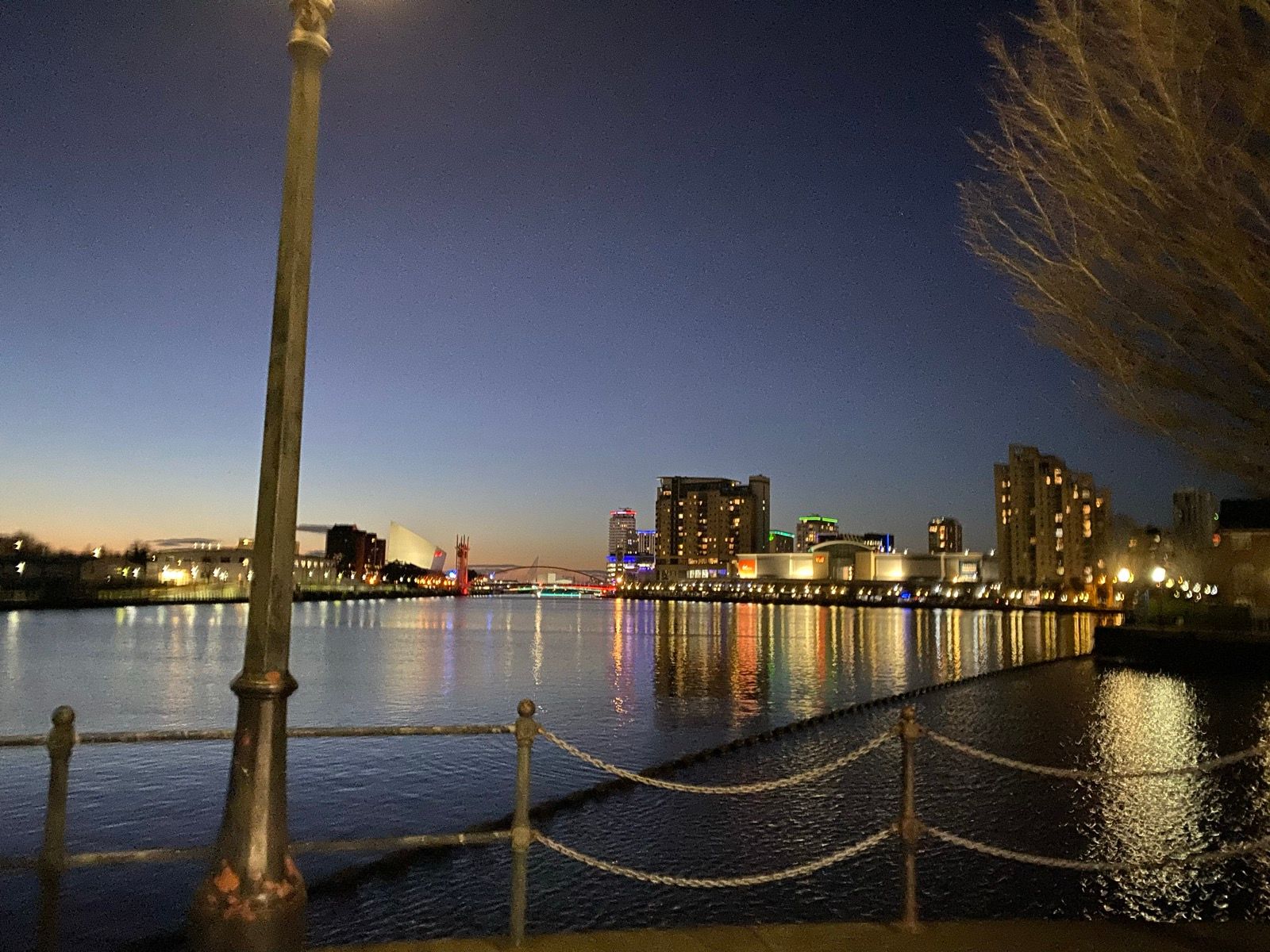 Waterfront and city buildings illuminated after dark.